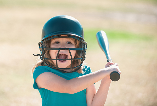 Funny kid up to bat at a baseball game. Close up portrait.