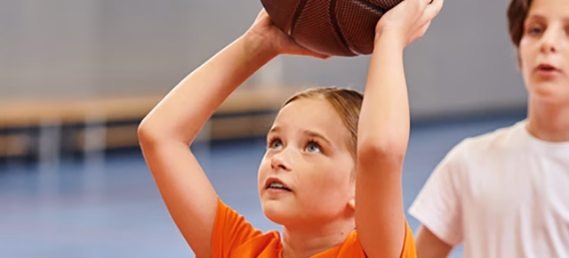 young child shooting basketball