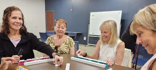 Active adults participating in various drop-in activities like Mahjong, Brain Games, knitting, and crafts.