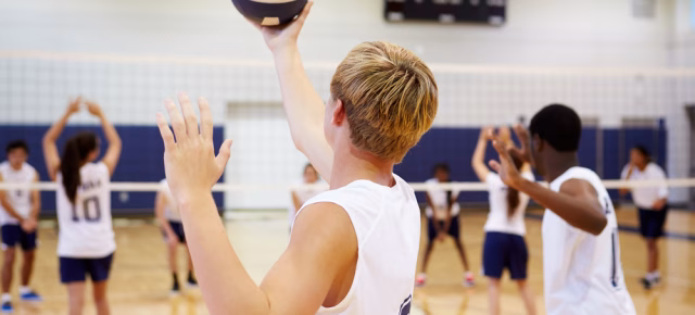 young adult man serving volleyball