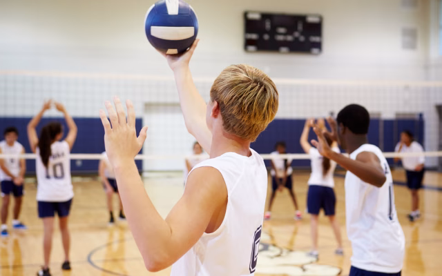 young adult man serving volleyball
