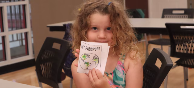 Young girl holding up a paper passport