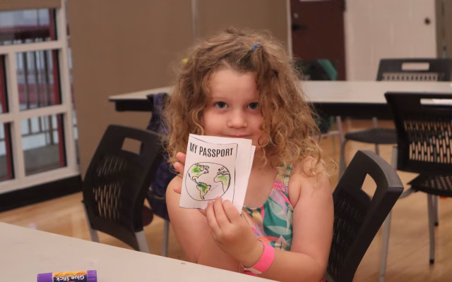 Young girl holding up a paper passport