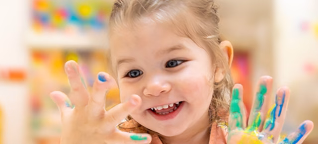 Preschool aged girl smiling with paint on her hands