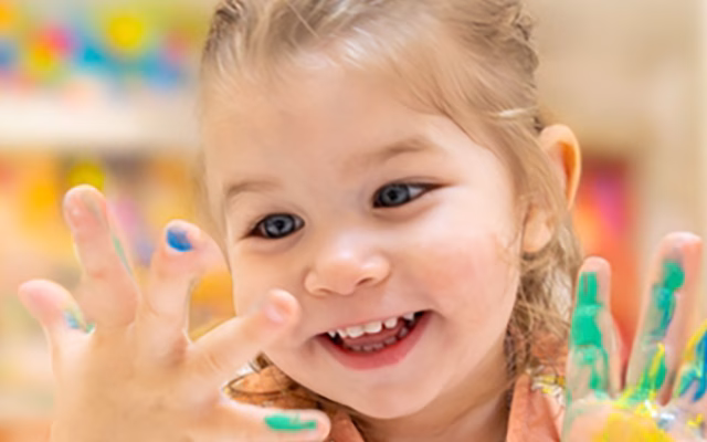 Preschool aged girl smiling with paint on her hands